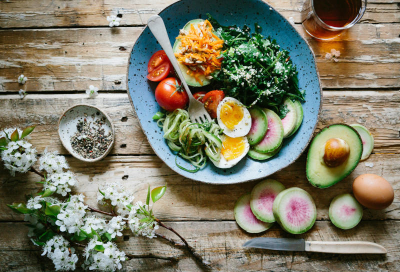 Une assiette garnie d'une salade et posée sur une table en bois.