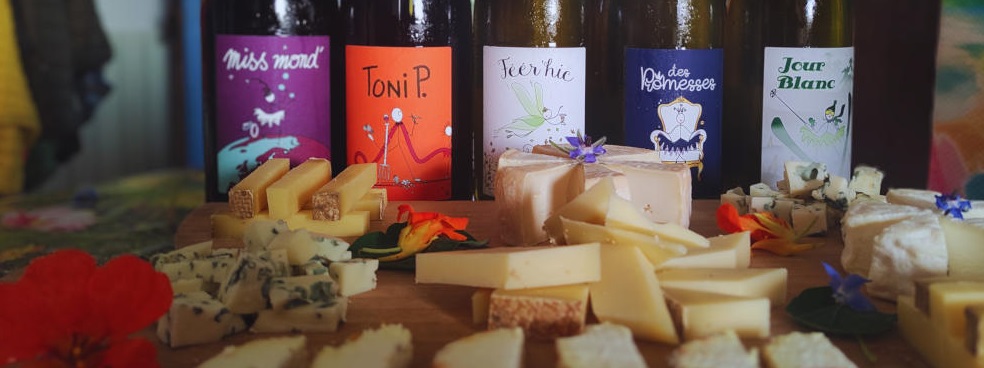 5 bouteilles de vins sont alignées ainsi qu'un plateau de fromages.